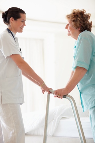 Nurse helping an old patient to stand on a Zimmer frame